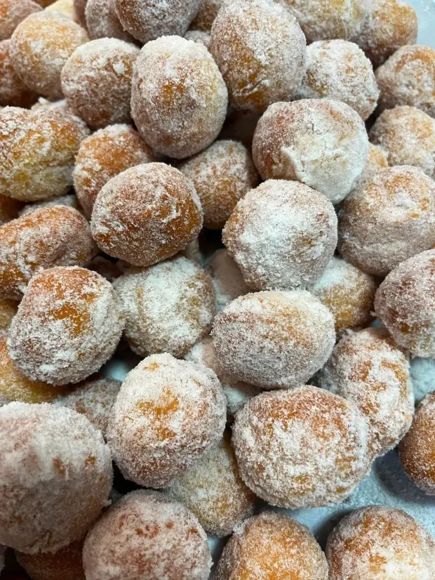 Bolinhos fritos passados no açúcar, ainda amontoados na bandeja