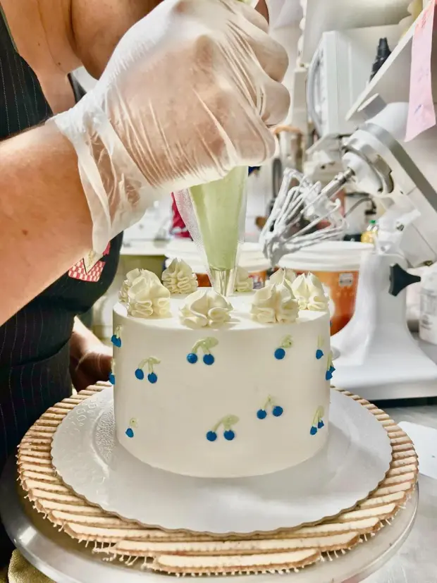 Bolo branco recebendo o bico de confeitar na cozinha da padaria
