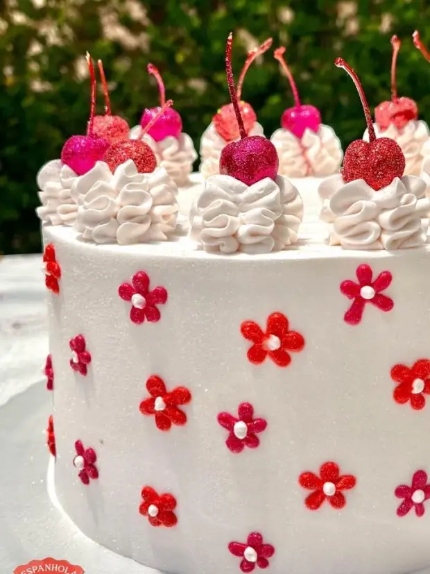 Bolo branco com florzinhas vermelhas e cerejas por cima