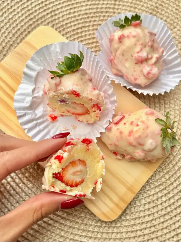 Bombons de morango cobertos de chocolate branco, um deles partido ao meio