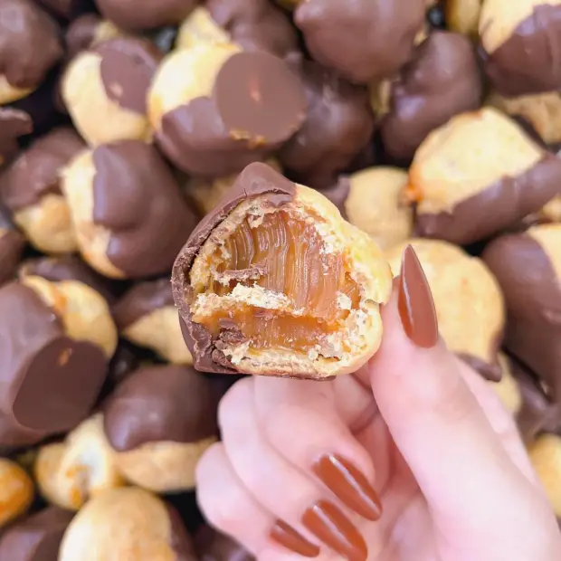 Carolina recheada de doce de leite e coberta de chocolate, partida ao meio