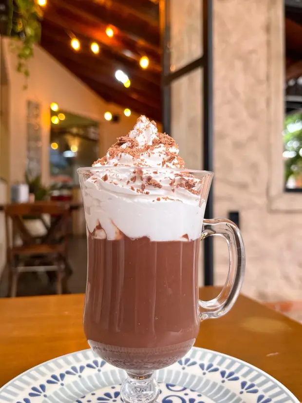 Chocolate quente com chantilly e raspas de chocolate, na taça de vidro