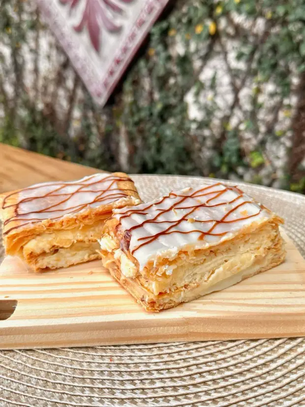 Folhado de creme com glacê branco e fios de doce de leite por cima