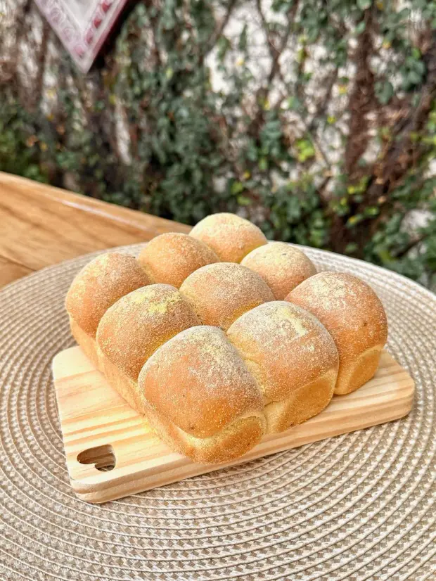 Pão caseiro de forma, com fubá por cima, na tábua de madeira