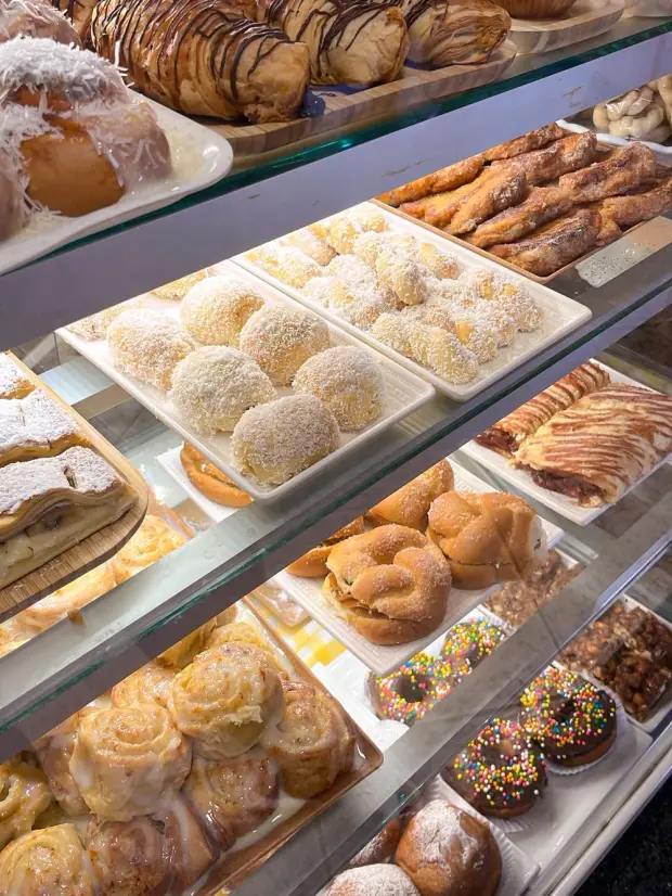 Vitrine da padaria cheia de folhados, sonhos de coco e rocamboles